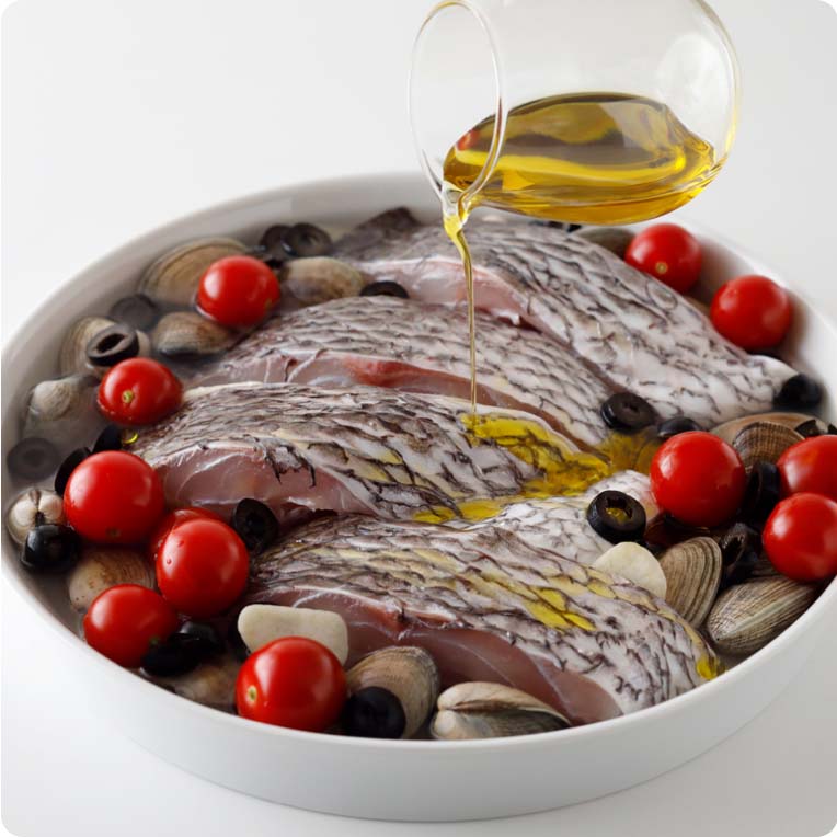 耐熱容器にあさり、ミニトマト、ブラックオリーブ、にんにくを入れて鯛の切り身を並べる。白ワインと水を注ぎ、鯛の切り身の上にオリーブオイルを回しかける。