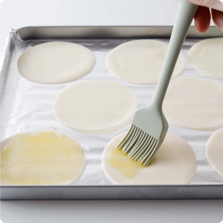 天板に餃子の皮を並べ、オリーブオイルを塗る。