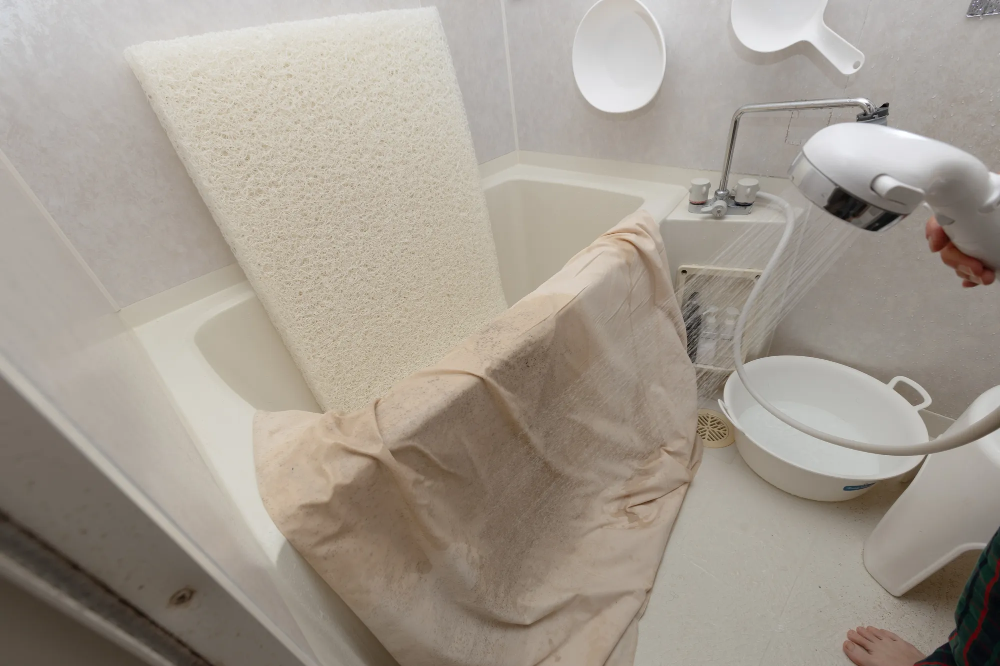 マットレスを風呂場で洗っている写真